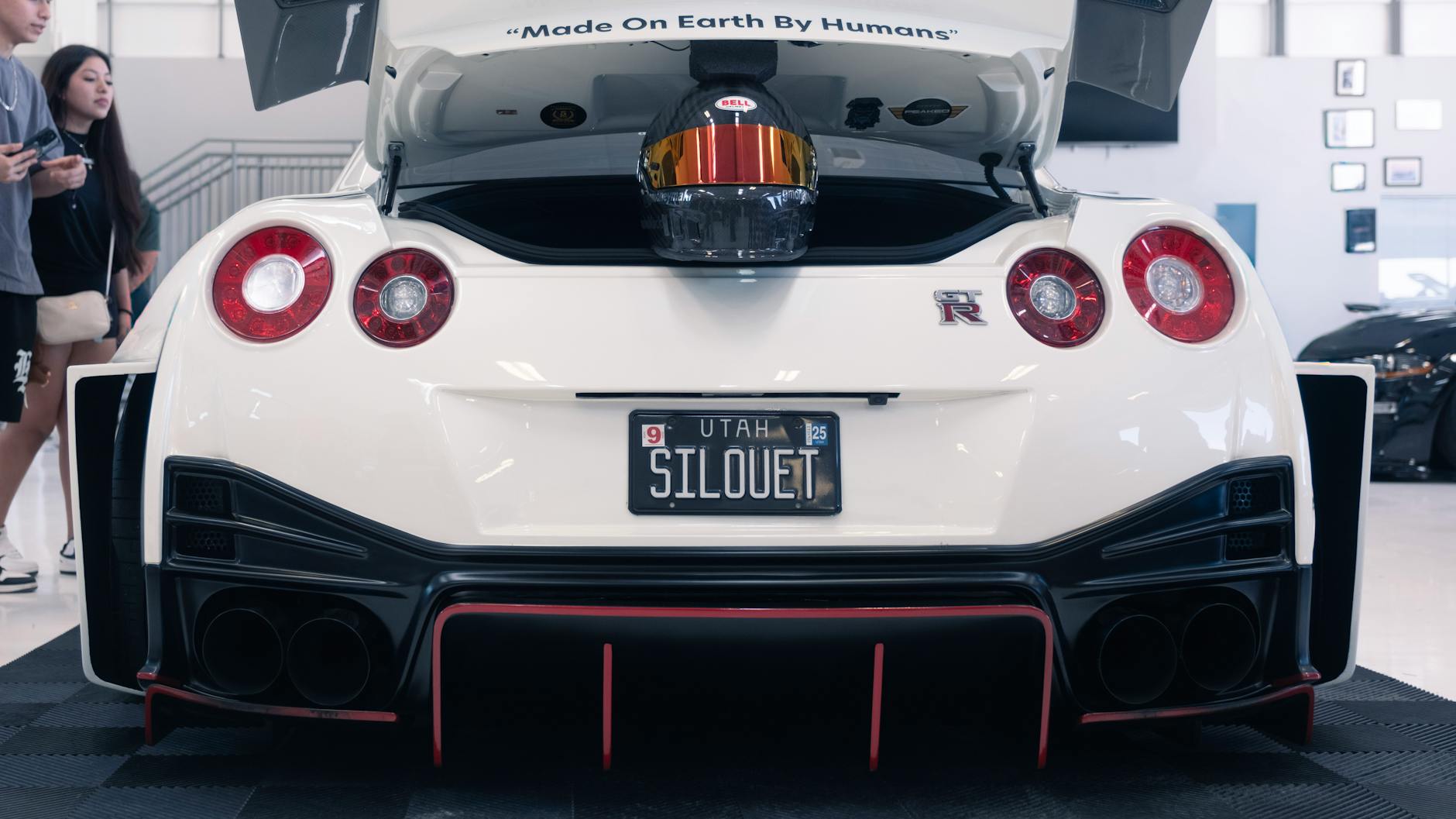 driver wearing racing helmet and harness in a Nissan GT R