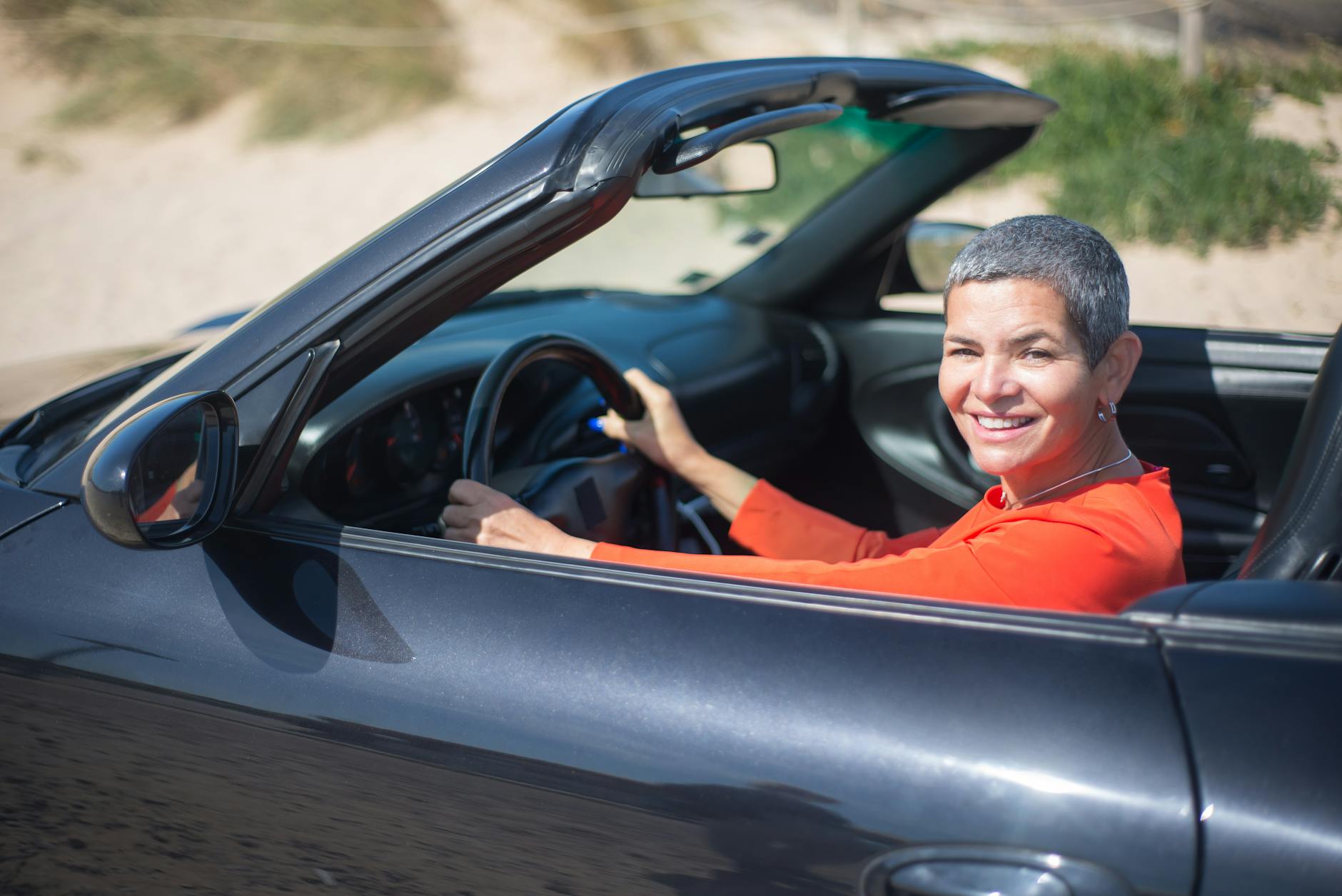 driver enjoying a sunny day in a Porsche 911 Cabriolet with the top down