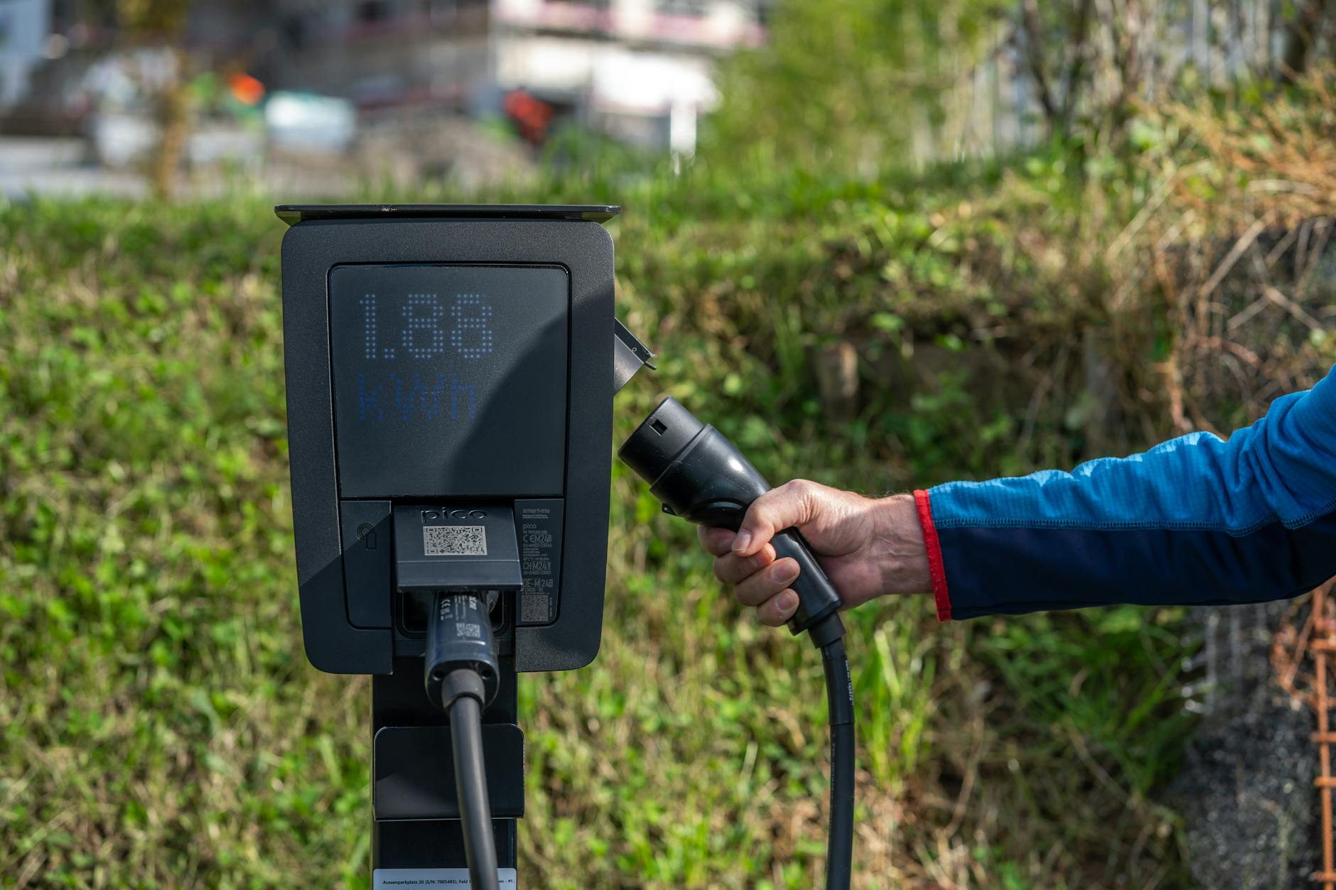 driver checking the charging status of their Hyundai Kona Electric at a public charging point